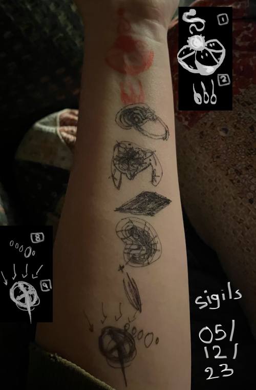 sigils, doodled with pen on the inside of an arm. they're scribbled and difficult to make out.